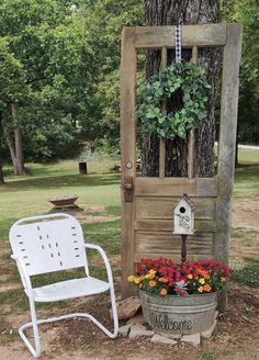 a white chair sitting next to a tree and a potted plant with flowers on it