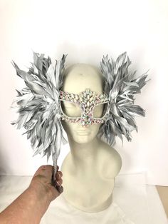 Mask with stick- Rhinestone mask- Masked ball- Wedding- New Years Eve - Bridal- Ice Queen- Masquerade Ball- Mardi Gras Hello, Perfect for a birthday celebration, costume party, New years eve celebration and then later hang it on a wall. AB...rainbow stones Clear stones. One size fits all adults. ---------------------------------- This listing is Silver Feather and Stick ribbon color. Custom colors please email me for silver, rose gold, copper or pastel colors. ----------------------------------- Silver Full Face Mask For Masquerade, Silver Full Face Masquerade Mask, Full Face Silver Masquerade Mask, Rhinestone Mask, Flower Headpiece Wedding, Masquerade Theme, Silver Mask, Feather Mask, Masked Ball