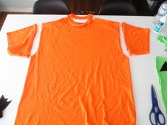 an orange shirt sitting on top of a white table next to scissors and other items