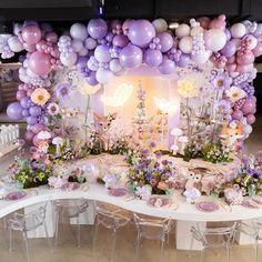 a table topped with lots of balloons and flowers next to a white bench filled with chairs