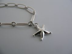 Overview:Offered for sale is a wonderful and gorgeous Tiffany and Co. Sterling Silver Peretti Starfish Link Bracelet. The piece is made from bright Tiffany sterling silver, yet has a very delicate and feminine feel to it. Hanging from its Tiffany Sterling Silver link chain is a whimsical and very pretty starfish. The piece is quite hard to find and come by, so grab it while you have the chance! It is very pretty worn on its own, but would also work very well with other jewelry that you already o Silver Link Chain, Tiffany And Co, Gift Pouch, Bracelet Bangle, Tiffany & Co., Link Chain, Link Bracelets, Starfish, Bangle Bracelets