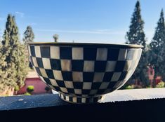 a black and white bowl sitting on top of a window sill next to trees