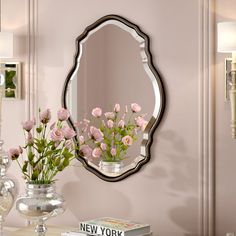 a mirror and vase with flowers on a table