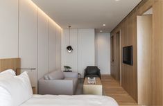 a living room with white walls and wood flooring next to a tv mounted on the wall