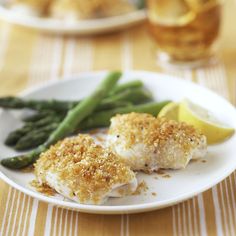 a white plate topped with fish and asparagus next to lemon wedges on a table