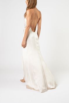 the back of a woman wearing a white dress with spaghetti straps and low cut neckline