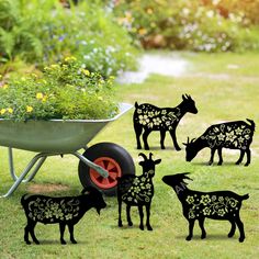 several farm animals are standing next to a wheelbarrow with flowers in the center