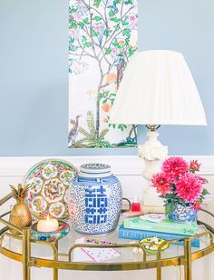 a blue and white vase sitting on top of a glass table next to a lamp