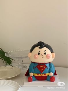 a cake that is shaped like a superman sitting on top of a table next to a plate