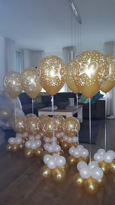 gold and white balloons are arranged in the shape of flowers on sticks with long tails