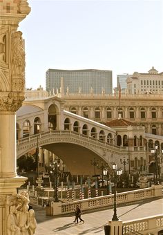 a person walking down a street in front of a bridge with buildings on both sides