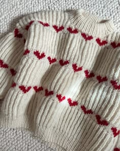 a white sweater with red hearts on it