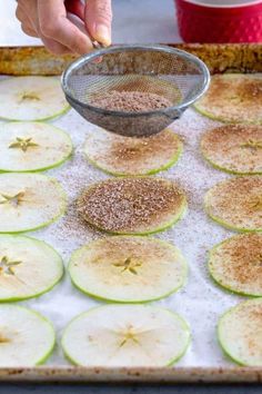 a person is sprinkling seasoning over sliced cucumbers on a baking sheet