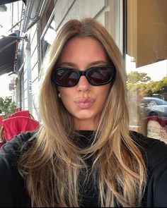 a woman with sunglasses on her face and long blonde hair is looking at the camera