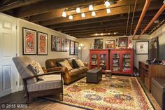 a living room filled with furniture and pictures hanging on the wall above an area rug