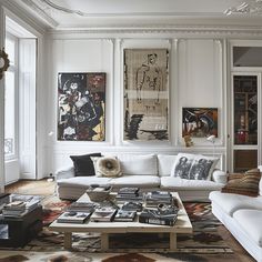 a living room filled with white furniture and pictures on the wall above it's coffee table