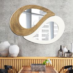 a wooden table with chairs and a round mirror on the wall