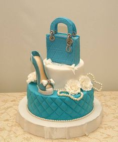 a blue and white wedding cake with high heel shoes on the top, pearls around the bottom