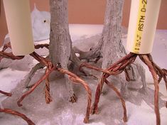 three candles are wrapped in twine and placed next to each other on snow covered ground