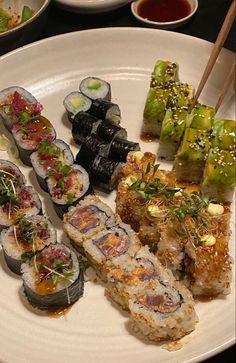 a white plate topped with different types of sushi and chopsticks on top of it