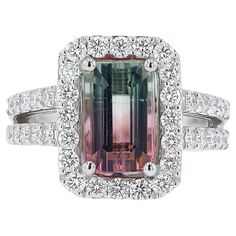 Our gemologist gushed over the fascinating color gradient of this 4 carat emerald cut watermelon tourmaline. Fashioned as a diamond studded cocktail ring (or gemstone engagement ring) by the Belrose Estate Jewelers design team of 18 karat white gold with a prominent halo and v shape band. The perfect gift for her as a bridal ring, anniversary or birthday present, this will be a lasting legacy to be enjoyed everyday. Condition: New Era: Contemporary Year: 2024 Metal: 18k White Gold Gemstone: Tourmaline Carat Weight: 4.02 Cut: Emerald Color: blueish Green - Pink Clarity: Transparent Accent Diamonds:  40 Round Brilliants 1.16 carats total Color: SI1 Clarity: G - I Graded by GIA standards Ring Size: 7, sizing available Rise Above Finger: 7mm Ring Face: 16mm L x 12mm W Band Width: 3mm (tapers f Custom Ring Box, Gemstone Engagement Ring, Cut Watermelon, Contemporary Ring, Etsy Gold Ring, Color Gradient, Emerald Color, Gemstone Engagement, Watermelon Tourmaline