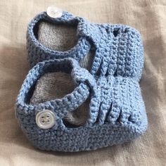 a pair of blue crocheted shoes sitting on top of a bed