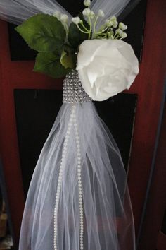 a white rose is attached to the back of a veiled door handle with pearls