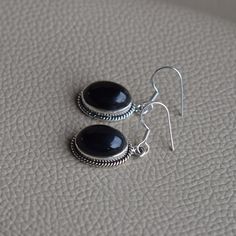 Gemstone-Black Onyx Shape-Oval Stone Size-10x14 MM Metal-925 Sterling Silver This One of a kind earrings is adorned with beautiful Black Onyx gemstone in sterling silver.Black Onyx is the birthstone representing the month of December. About gemstone- Black Onyx is the birthstone for Leo. It is the stone of protection.This elegant smooth textured stone is said to have immense healing and spiritual benefits.Black Onyx symbolizes peace,harmony and love and good luck.Black Onyx is well known to remo Black Sterling Silver Jewelry With Oval Cabochon, Black Oval Cabochon Sterling Silver Jewelry, Nickel-free Black Oval Jewelry, Elegant Black Oval Nickel-free Jewelry, Black Oval Earrings For Formal Occasions, Classic Black Oval Earrings, Black Oval Pierced Earrings, Black Onyx Oval Earrings, Black Oval Handmade Earrings