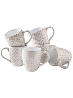 four coffee mugs sitting next to each other on a white surface with an intricate design