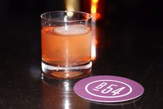 a close up of a glass of alcohol on a table with a drink in the background