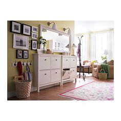 a white dresser sitting next to a living room filled with furniture and pictures on the wall