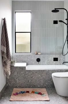 a bath room with a toilet a tub and a shower head mounted to the wall