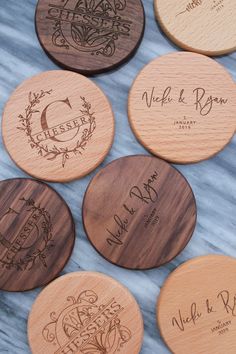 engraved wooden coasters with names on them sitting on a marble countertop in front of a blue background