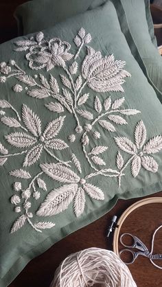 a close up of a pillow on a table next to some yarn and scissors in front of it