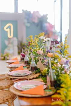 a long table with place settings and flowers on the top, along with paper decorations