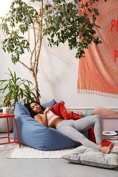 a woman laying on top of a bean bag chair next to a potted plant