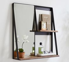 a mirror sitting on top of a wooden shelf next to a potted plant and book