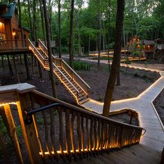 a wooden staircase leading to a tree house in the woods at night with lights on it