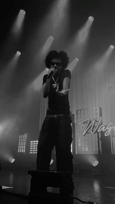 a man standing on top of a stage with his hands in the air while holding a microphone