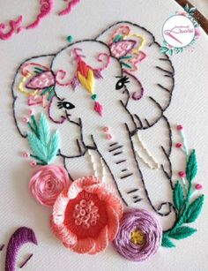 an elephant with flowers on it's head is embroidered onto a piece of fabric