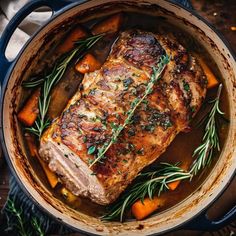 pork chops in a pot with carrots and rosemary garnish on the side