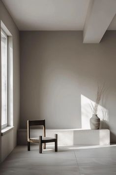 a chair sitting in front of a window next to a potted plant