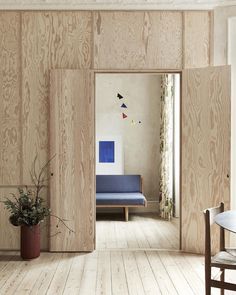 a room with wood paneling and a blue chair in the corner next to a potted plant