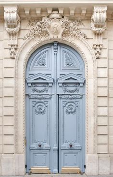 two blue doors are open in front of a stone building with ornate carvings on it