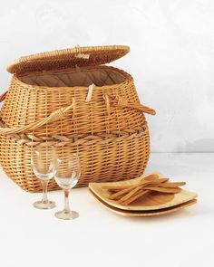 a wicker basket with wine glasses and napkins next to it on a white surface