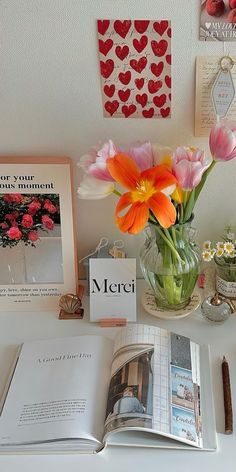 a table topped with books and flowers on top of a white counter covered in pictures