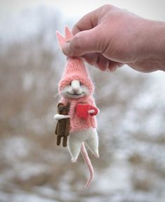 a hand holding a small stuffed animal with a cup