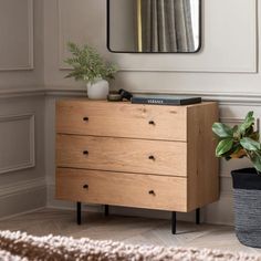 a wooden dresser sitting next to a mirror and potted plant on top of it