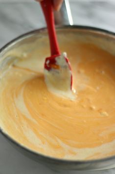 a person using a toothbrush to brush their teeth in a bowl with orange liquid