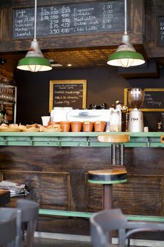 the interior of a coffee shop with wooden tables and stools in front of it